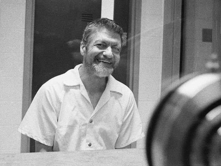 a black and white photo of a man in front of a mirror smiling at the camera