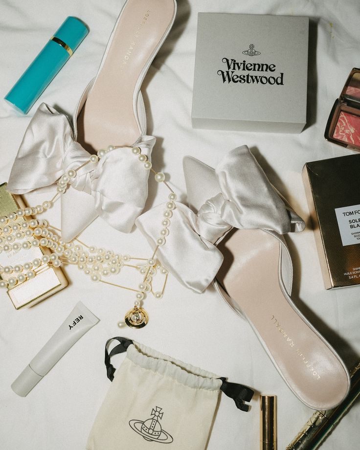 the contents of a woman's purse and shoes laid out on top of a bed