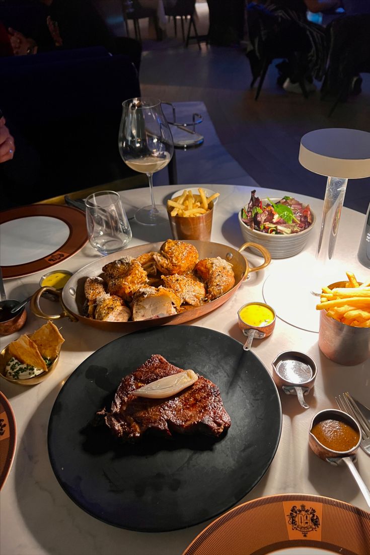 a table topped with plates and bowls filled with food covered in sauces, meat