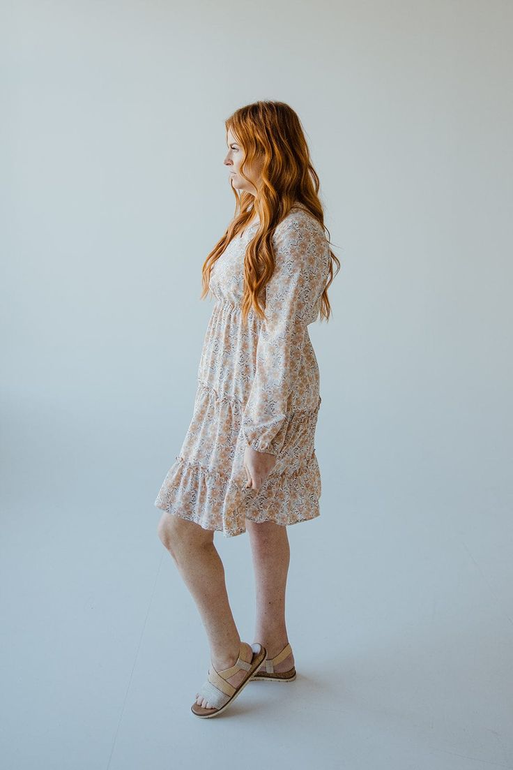 This beautiful neutral midi-length dress has all of the boho vibes! It is going to be your new go-to for date nights, weddings, and work events. This dress features a modest, shorter v-neckline and fluttery blouson long-sleeves. The blousy material flows beautifully down the dress's skirt, with the bottom featuring a tiered effect edged by ruffles. The smocked waist gives the dress an a-line fit that will accentuate your curves beautifully and provide structure to this extra flowy dress. The lin Flowy Boho Print Knee-length Dress, Flowy Knee-length Boho Dress With Boho Print, Flowy Knee-length Boho Print Dress, Flowy Knee-length Boho Dress, Spring Boho Knee-length Dress With Boho Print, Flowy Boho Print Midi Dress For Brunch, Feminine Spring Boho Mini Dress, Flowy Fall Floral Midi Dress, Feminine Boho Mini Dress For Spring