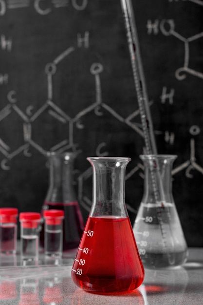 red liquid is in a beaker and several other flasks are lined up on the table