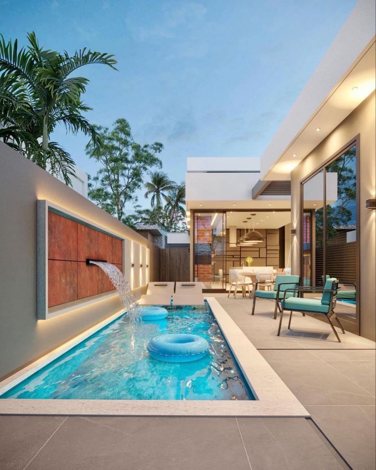 an outdoor swimming pool with water feature and lounge chairs