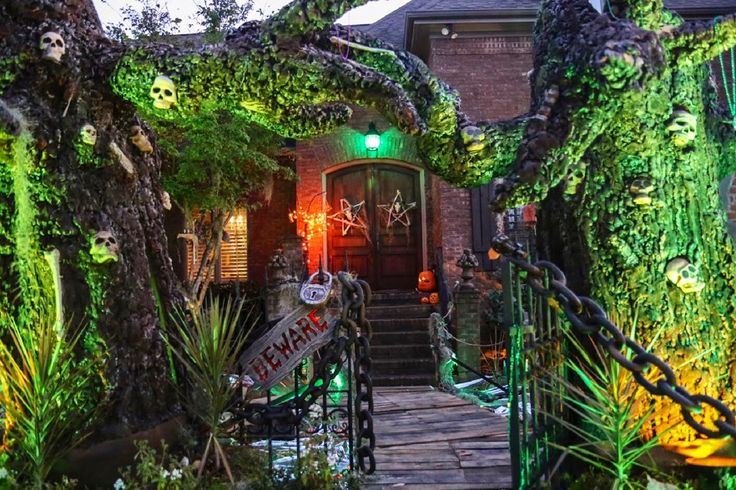 an entrance to a house covered in fake plants and trees with halloween decorations on them