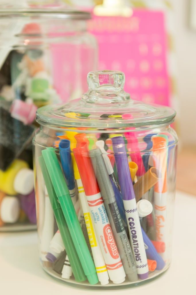 a glass jar filled with markers and crayons