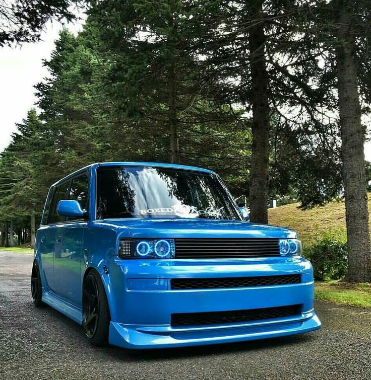 a blue car is parked in front of some trees