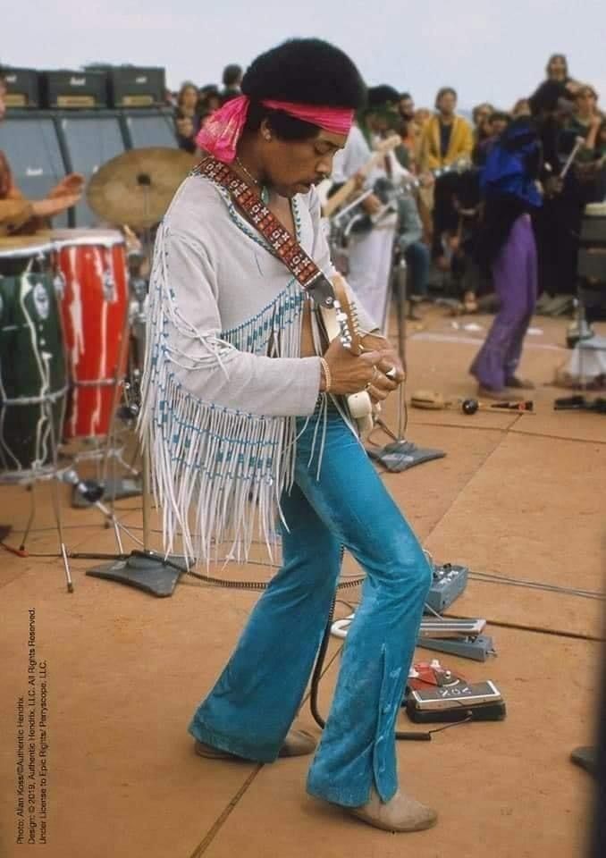 a man in white shirt and blue pants playing guitar