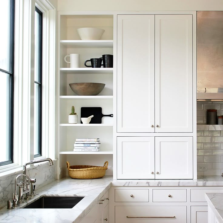 a kitchen with white cabinets and marble counter tops