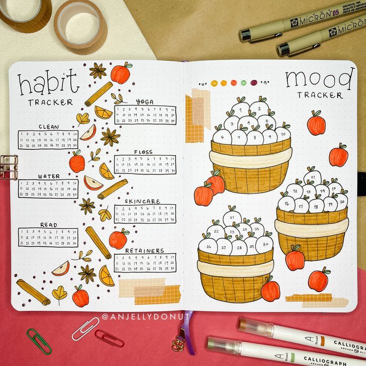 an open planner with oranges and apples on it next to some markers, pens and scissors