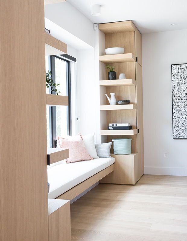 a living room filled with lots of furniture and bookshelves next to a window