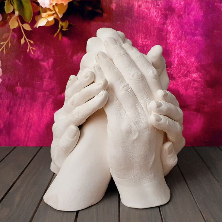 a white ceramic sculpture holding its hands together