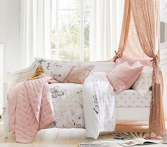 a white bed with pink sheets and pillows