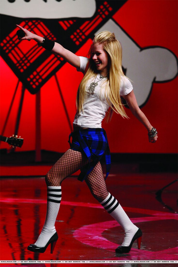 a woman in white shirt and blue skirt on stage with her arms out to the side