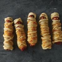 four hotdogs wrapped in bread with toppings on them are lined up next to each other