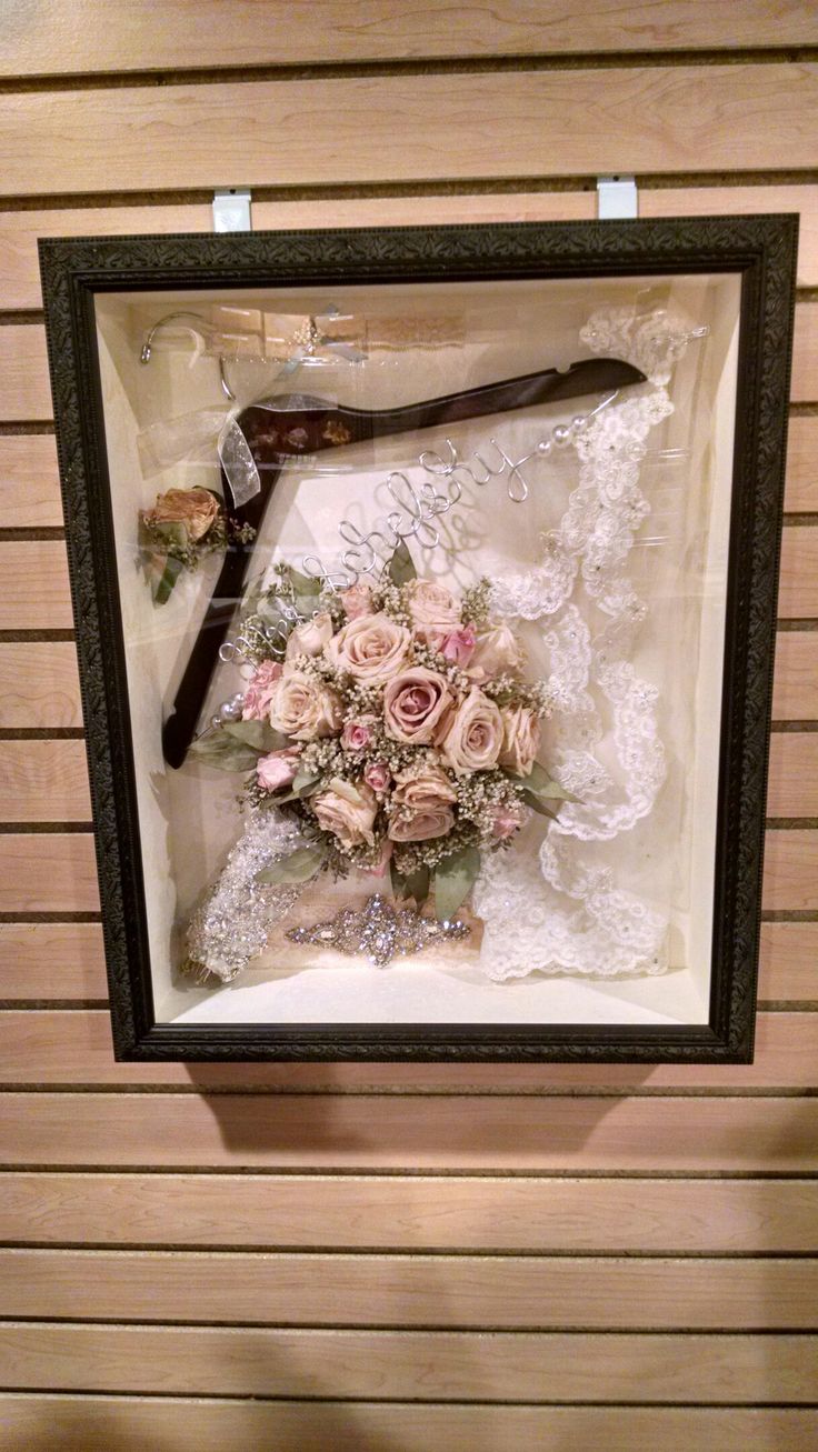 a bouquet of flowers in a frame hanging on the wall next to a pair of scissors