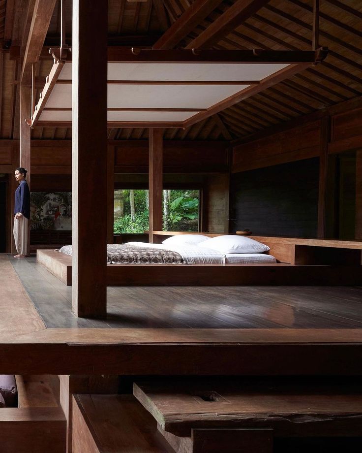 a person standing in the middle of a room next to a bed and desks