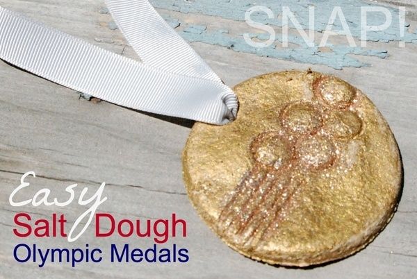 an olympic medal laying on top of a wooden table next to the words, easy salt dough olympic medals