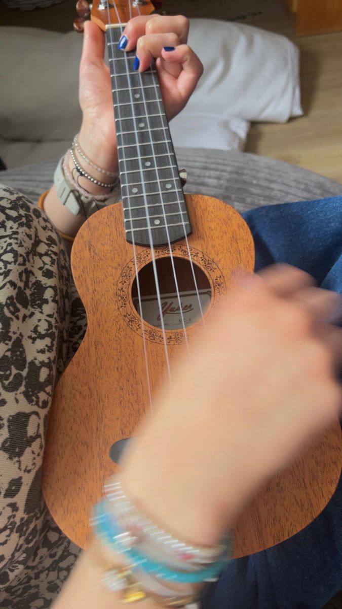 a woman is playing an ukulele on her lap and holding it up to the camera