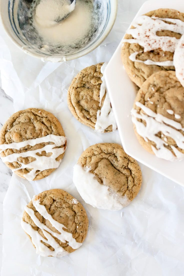 iced cookies with icing on white paper next to bowl of milk and spoons