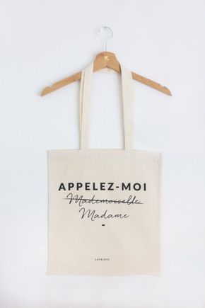 a tote bag hanging on a hanger with the words appelze - moi in cursive writing