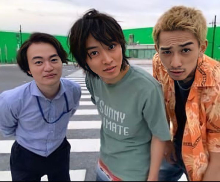 three young men standing next to each other in front of a crosswalk with green walls behind them