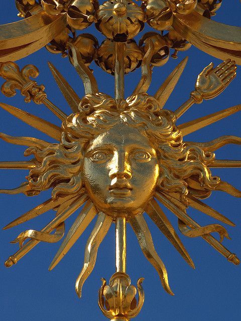 a golden sun face with ornate details against a blue sky