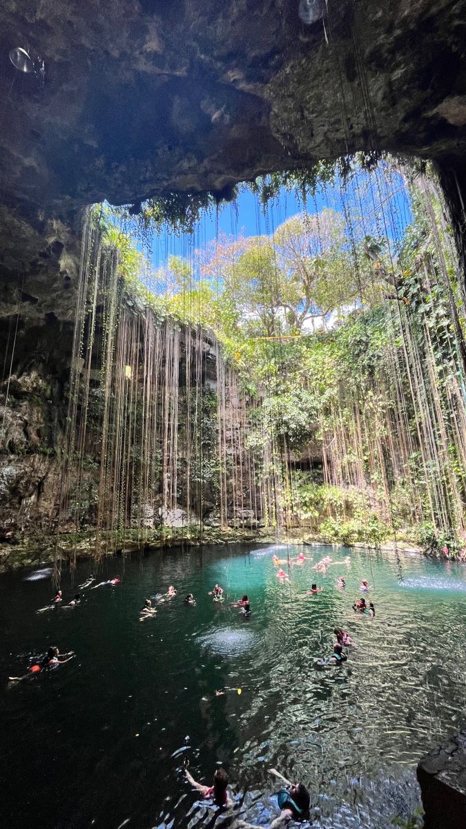 many people swimming in the water under a waterfall