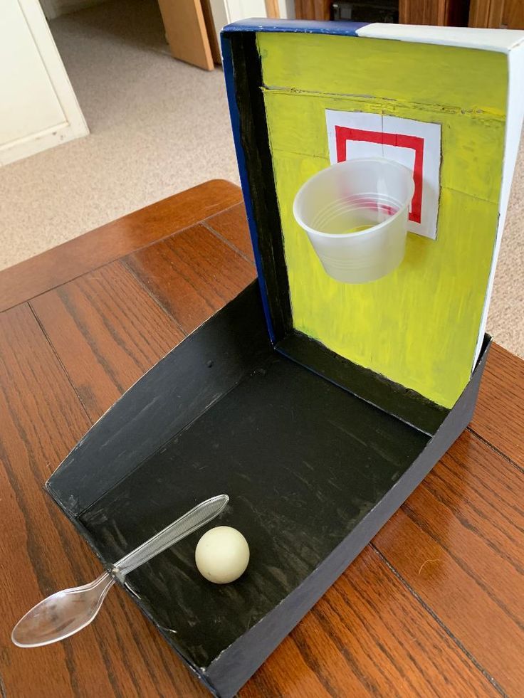 an open box with a spoon and bowl inside on a wooden table in a room