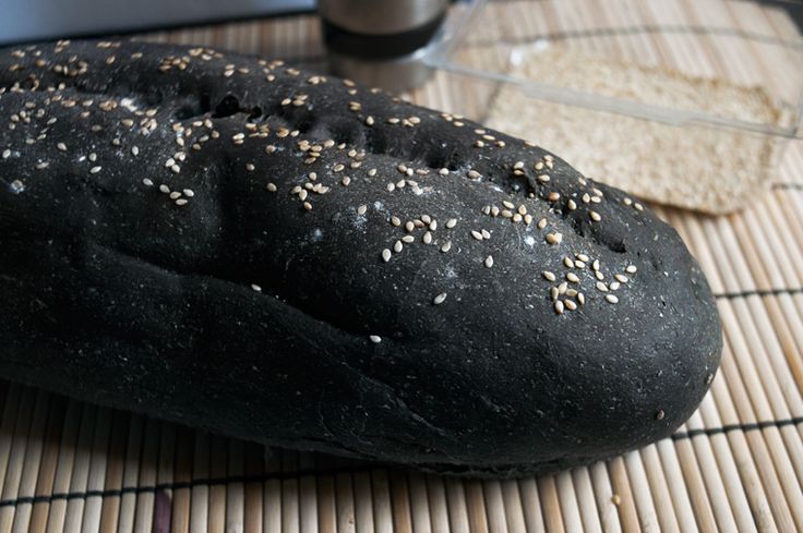 a loaf of sesame seed bread on a bamboo mat