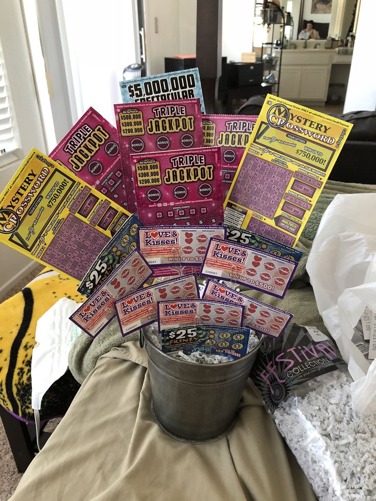 a bucket filled with lots of tickets sitting on top of a bed next to a window