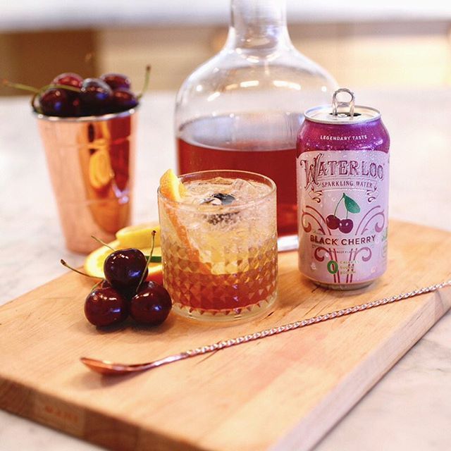 a wooden cutting board topped with drinks and fruit