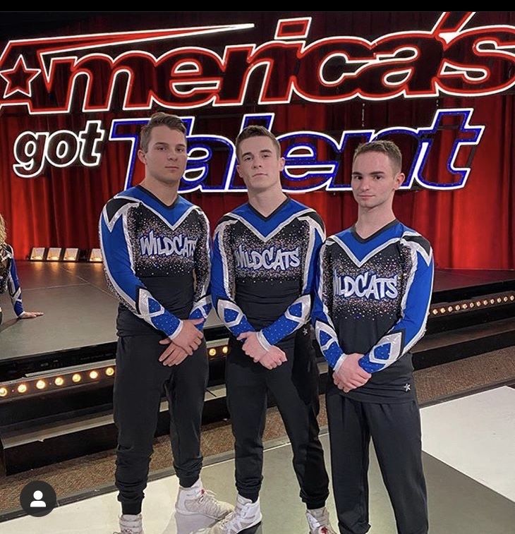 three young men standing next to each other in front of a stage