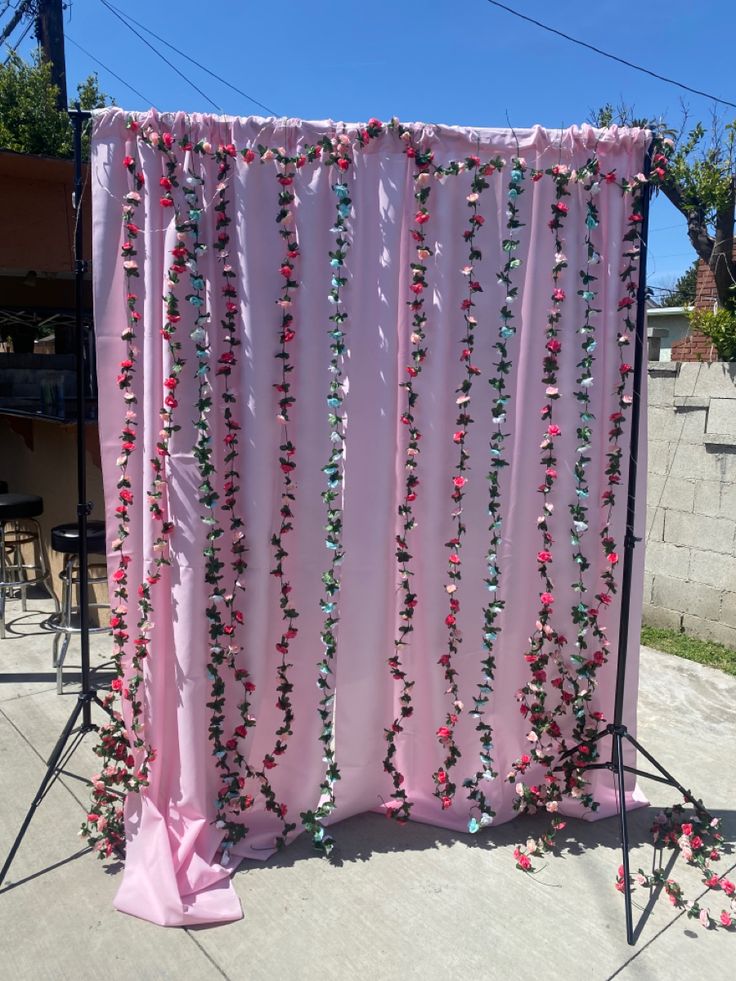 a pink backdrop with beads hanging from it's sides on a sidewalk in front of a house