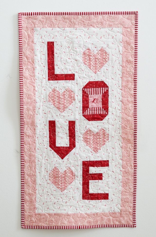 a red and white quilt with the word love on it