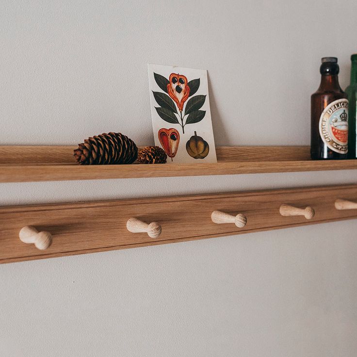 two wooden shelfs holding bottles and other items on top of each other, one with a pine cone