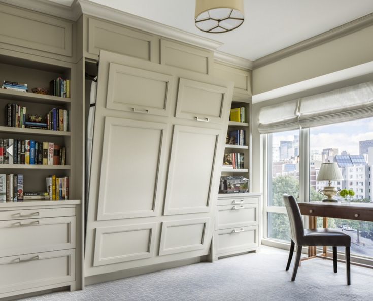 a dining room table and chairs with built in bookshelves next to the window