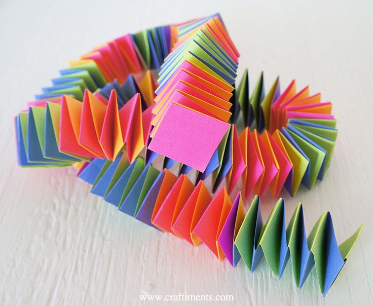 colorful folded origami pieces on white surface with pink post - it note stuck to them