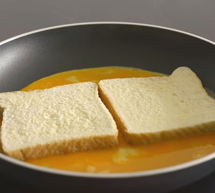 two pieces of bread sit in a pan with melted cheese on top, ready to be cooked