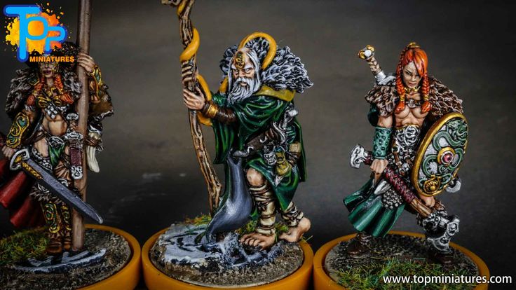 three painted figurines on top of yellow bases with one holding a staff and the other carrying a spear