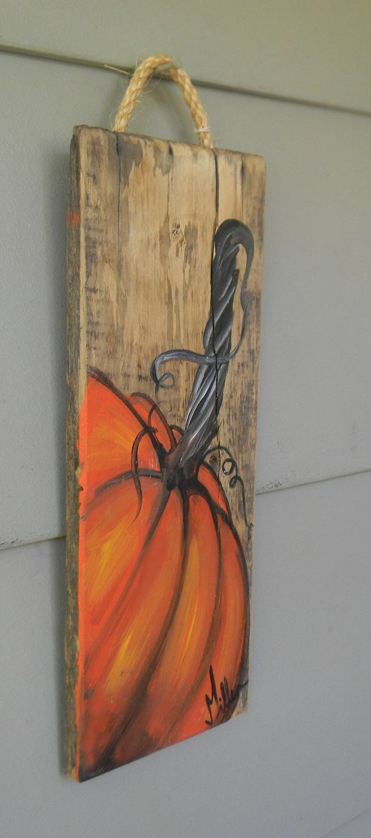 a wooden sign hanging on the side of a building with a pumpkin painted on it