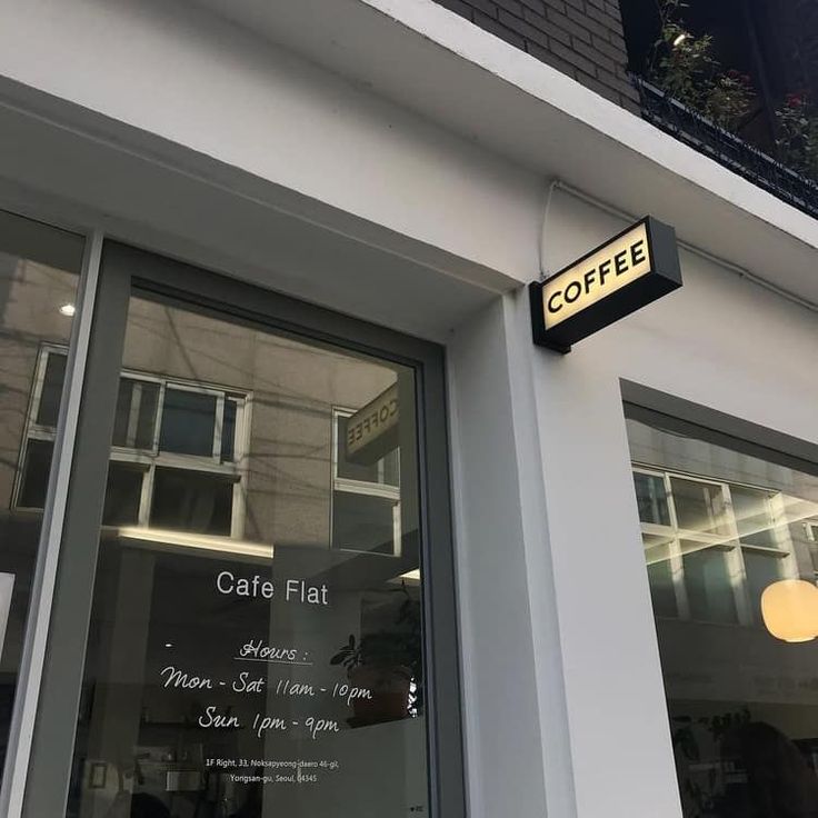 a coffee shop sign on the side of a building with glass doors and windows that read cafe flat