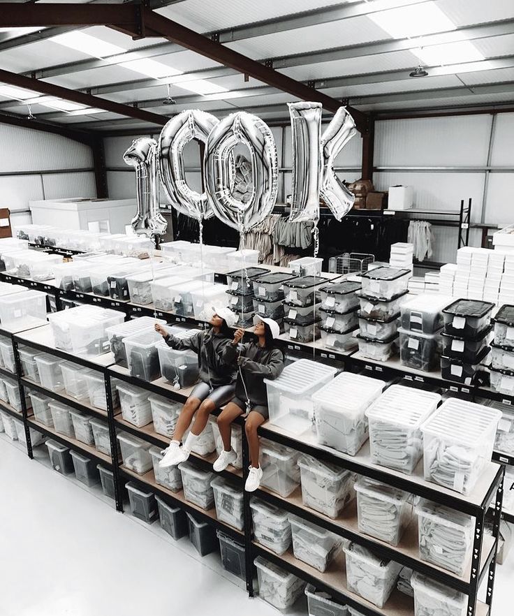 two people are sitting on some shelves in a warehouse