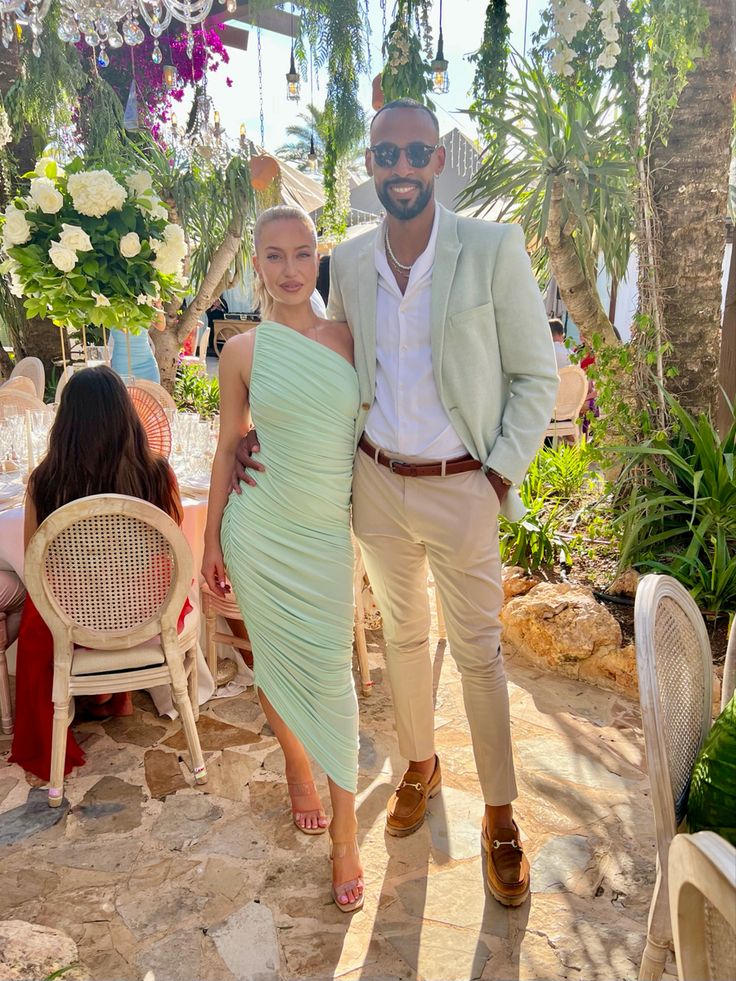 a man and woman standing next to each other in front of tables with flowers on them