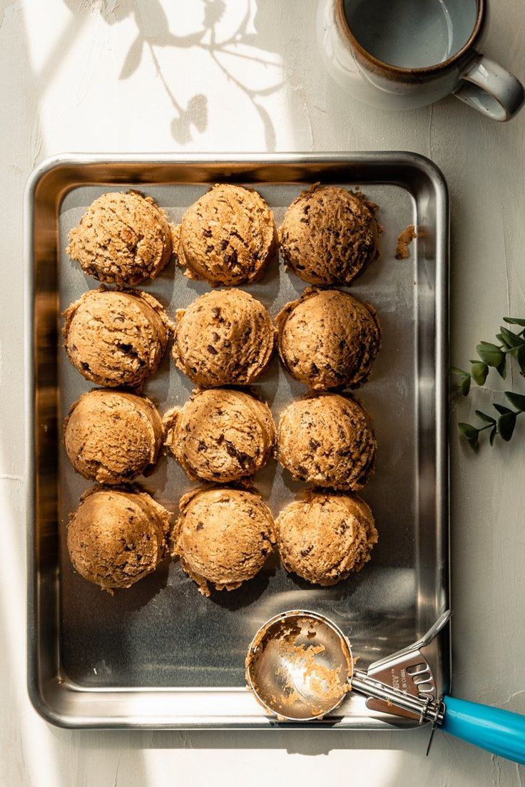 muffins on a baking sheet with a spoon and cup of coffee