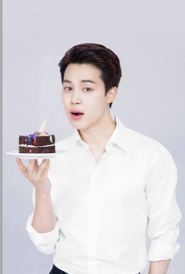 a man holding a piece of cake with candles on it in front of his face