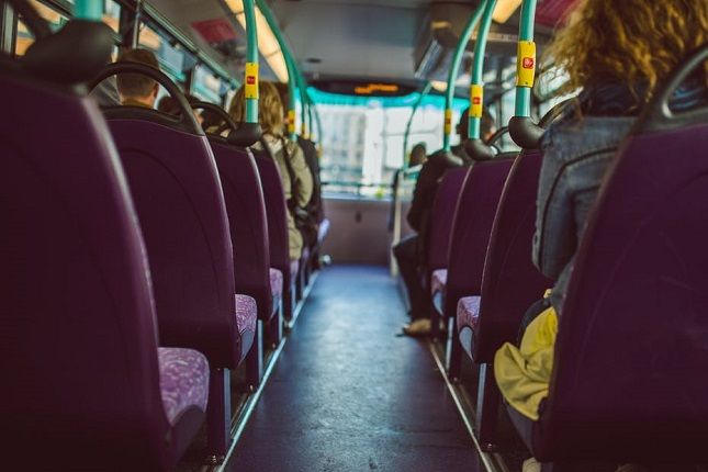 the interior of a bus with purple seats and yellow poles on each side, looking down at the floor