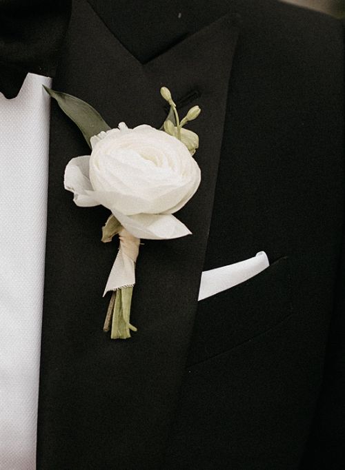 a man in a tuxedo is wearing a boutonniere with white flowers on it