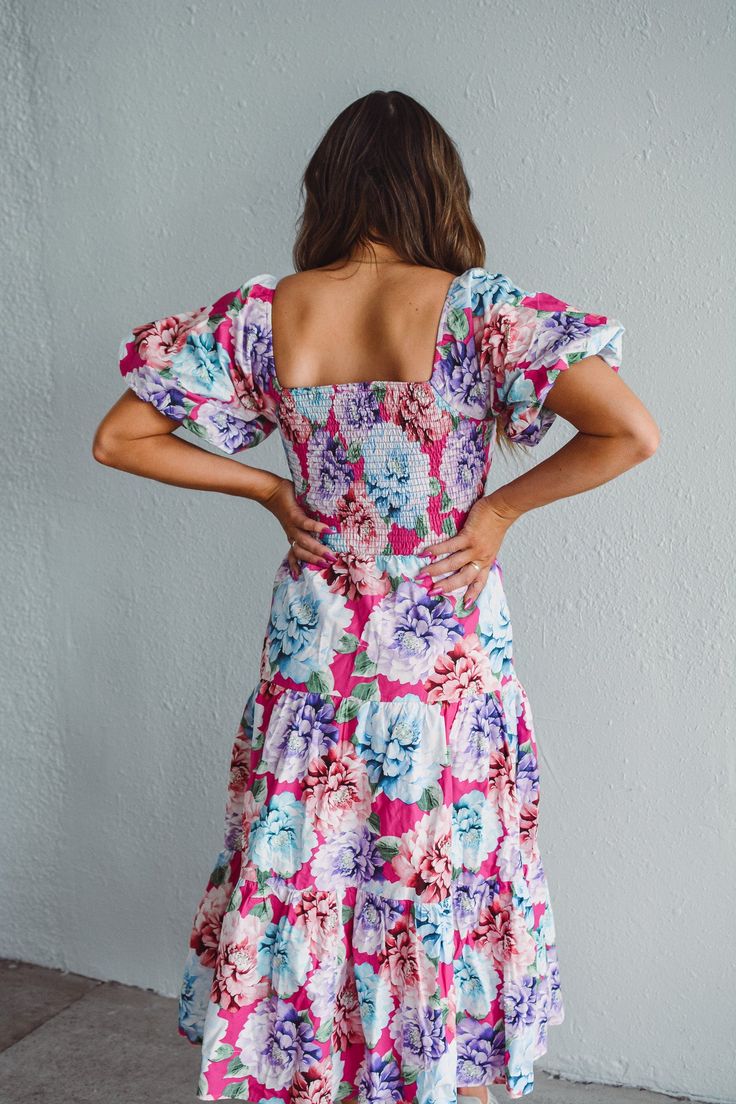 This Delightful Dahlia Dress features a long length that flatters all body types. The baby doll sleeves add a touch of femininity while the ruched back provides a comfortable and flattering fit. With cool colors and a beautiful floral print, this dress is perfect for any occasion. And with the added feature of pockets, you can carry your essentials with ease. Material: 100% Cotton, Lining 100% Polyester Care: Hand wash cold, do not bleach, line dry, iron low. Available in both the Fort Wayne and North Manchester boutique locations Don't forget! We're more than just a clothing boutique- we are a top-rated full-service florist operating in two locations. Need a floral delivery? Recently engaged? Or need flowers in a hurry? Check out our flowers tab for the full floral experience. Summer Midi Dress With Floral Print And Square Neck, Fitted Floral Print Puff Sleeve Dress For Casual Occasions, Floral Sundress With Smocked Back For Brunch, Pink Puff Sleeve Dress For Spring Vacation, Feminine Fitted Floral Dress With Smocked Back, Fitted Feminine Floral Dress With Smocked Back, Pink Puff Sleeve Smocked Dress For Garden Party, Pink Smocked Dress With Puff Sleeves For Garden Party, Multicolor Ruched Midi Dress For Garden Party