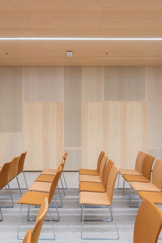 rows of chairs and tables in a room with wood paneling on the wall behind them