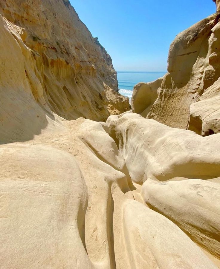 some very pretty rocks by the ocean and water with blue skies in the back ground