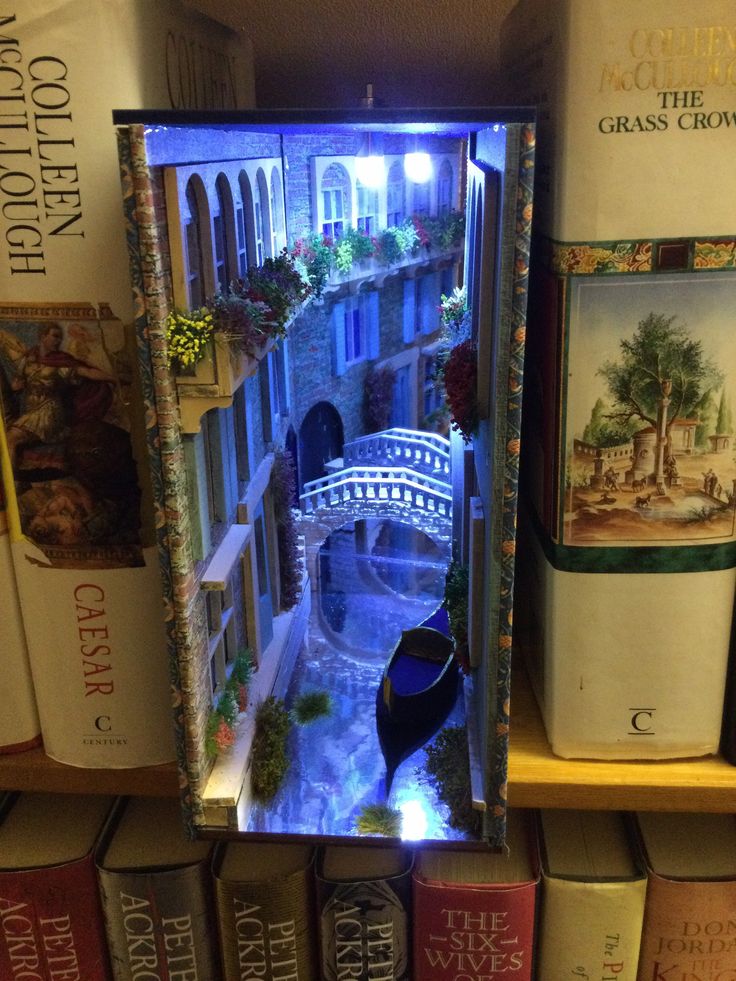 a book shelf filled with books and a miniature model of a bridge in the middle